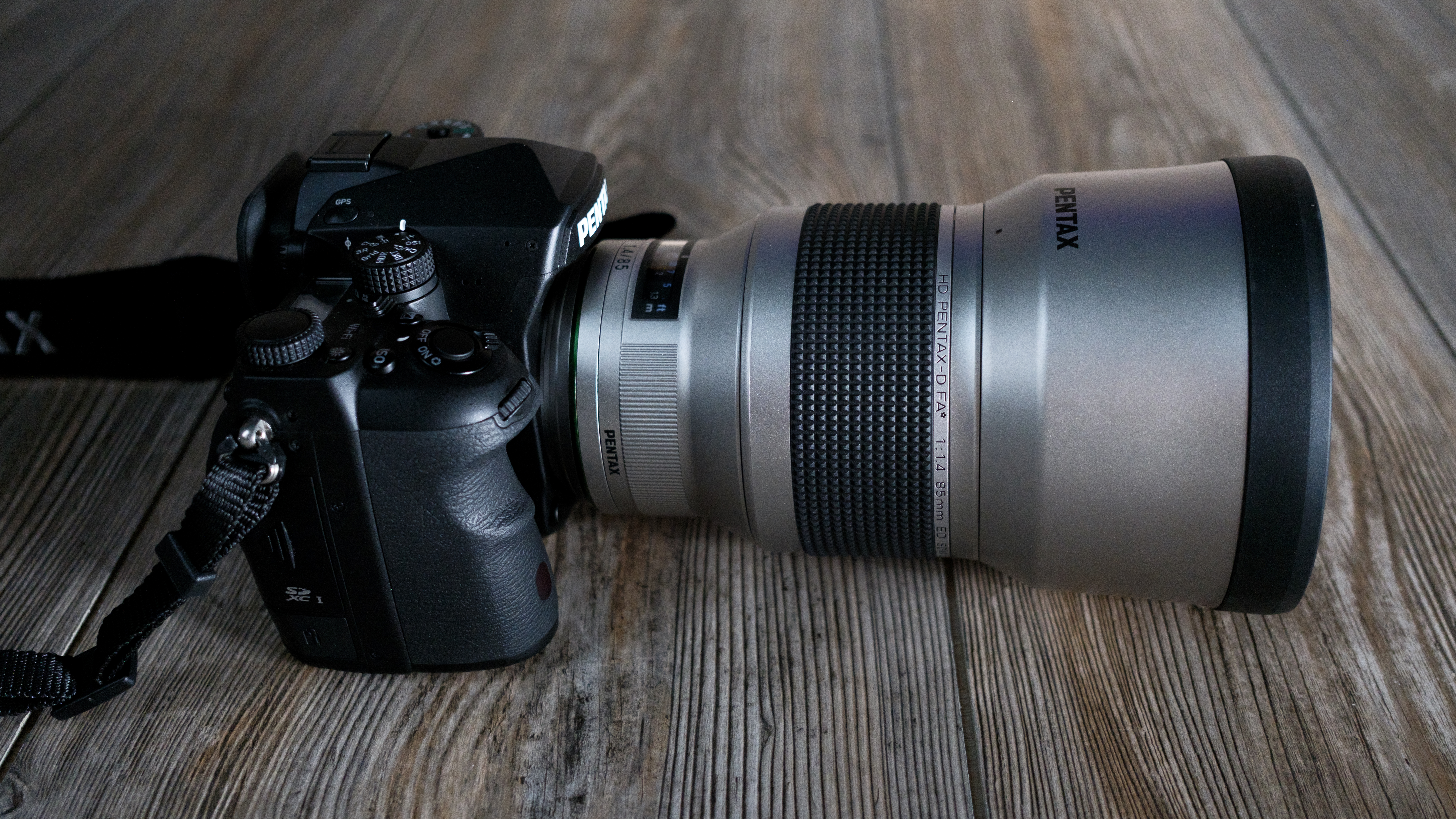 The Pentax 85mm f/1.4 SDM AW on a wood background