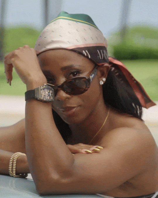 a gif of Shelly-Ann Fraser-Pryce wearing a headscarf and glasses looking at the camera