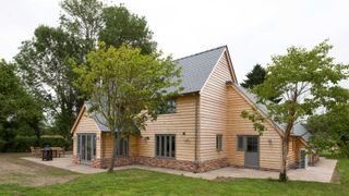 Border Oak timber clad home with air source heat pump to right