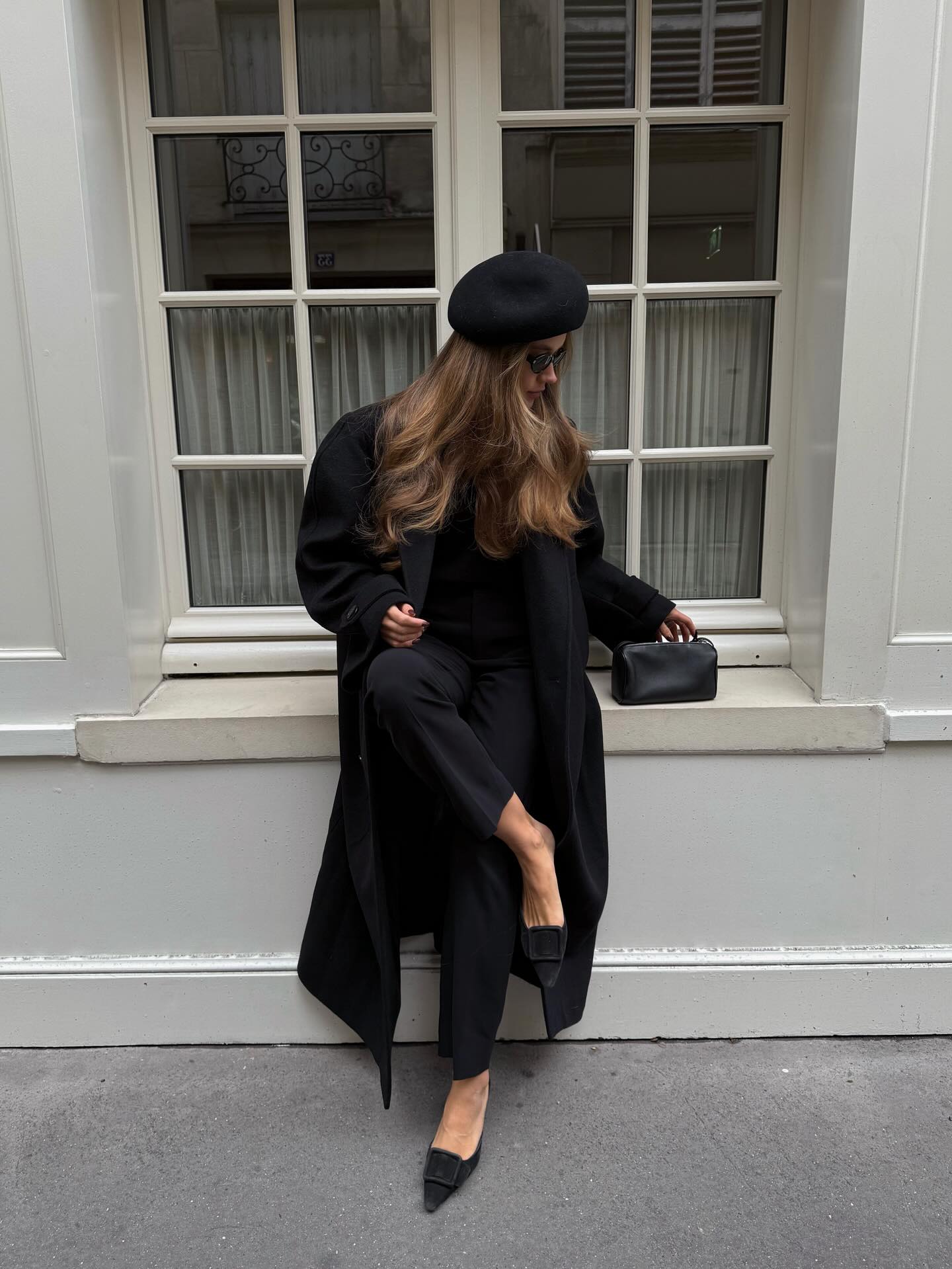 An image of @lovisabarkman wearing a pill box hat, long trench coat, and Manolo Blahnik Maysale mules.