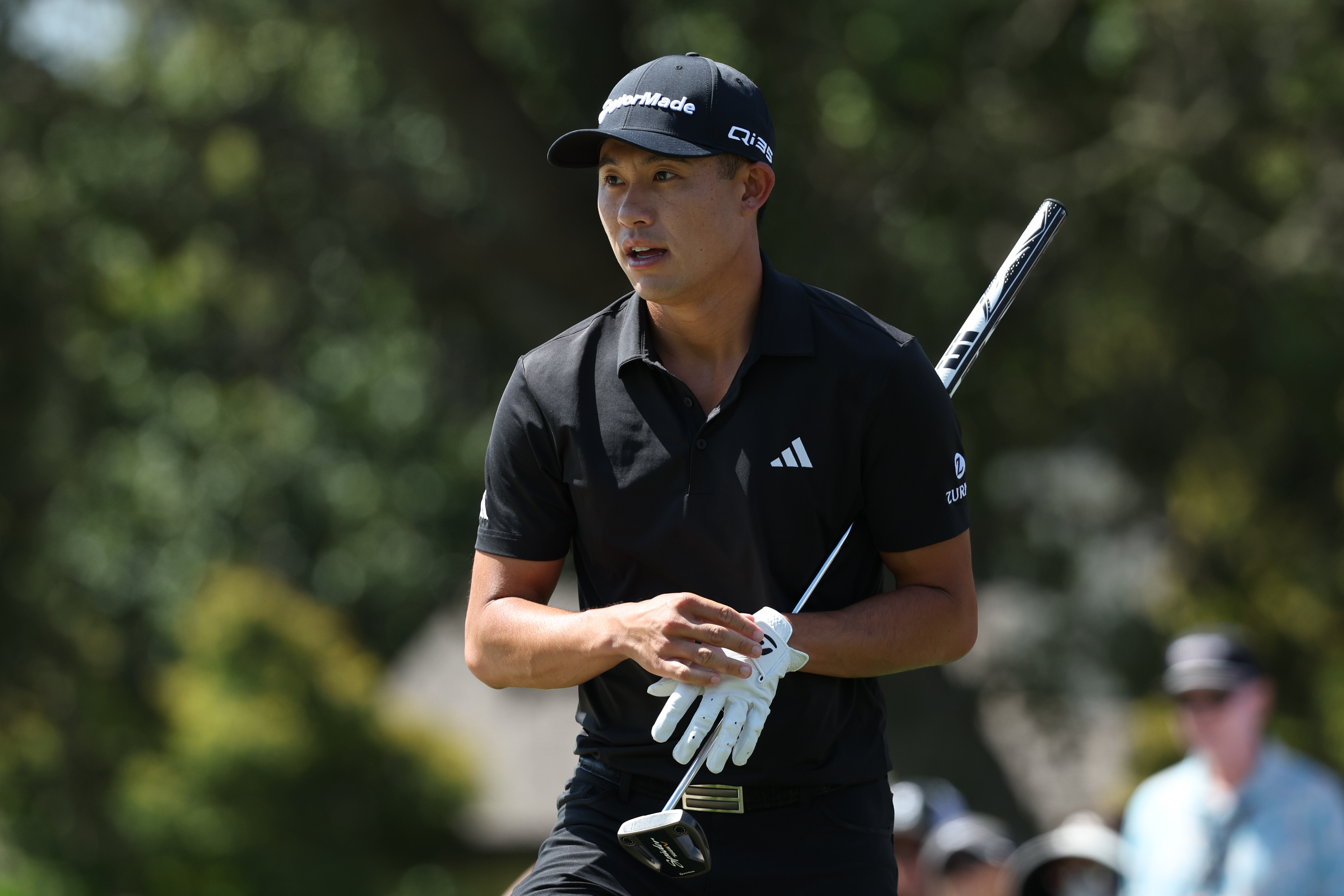 Collin Morikawa walks off the green holding a putter