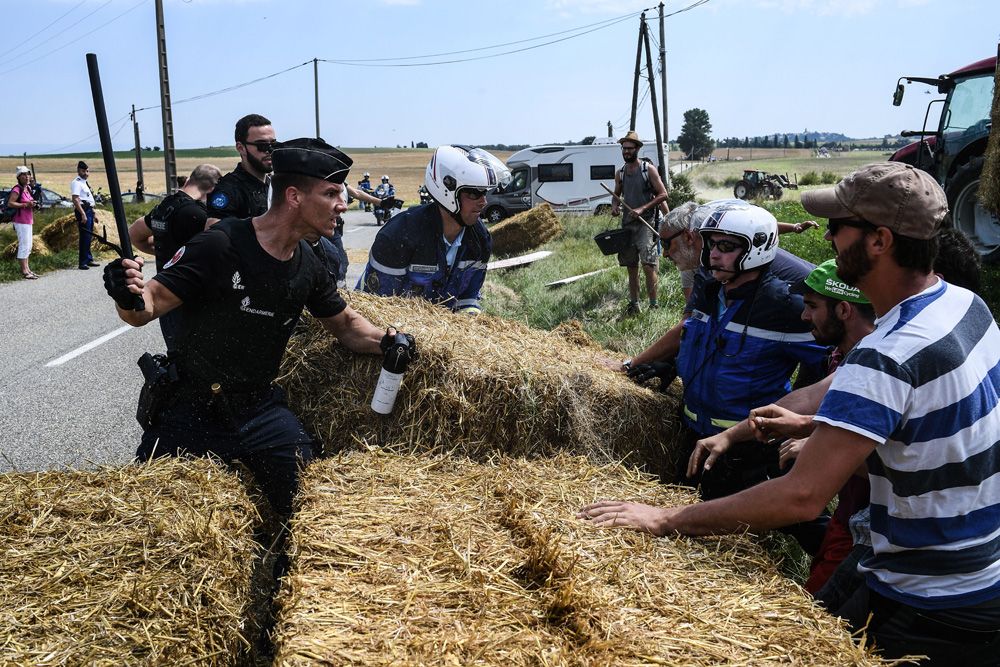 A French police officer with a baton and pepper spray tries to hold back the protesters
