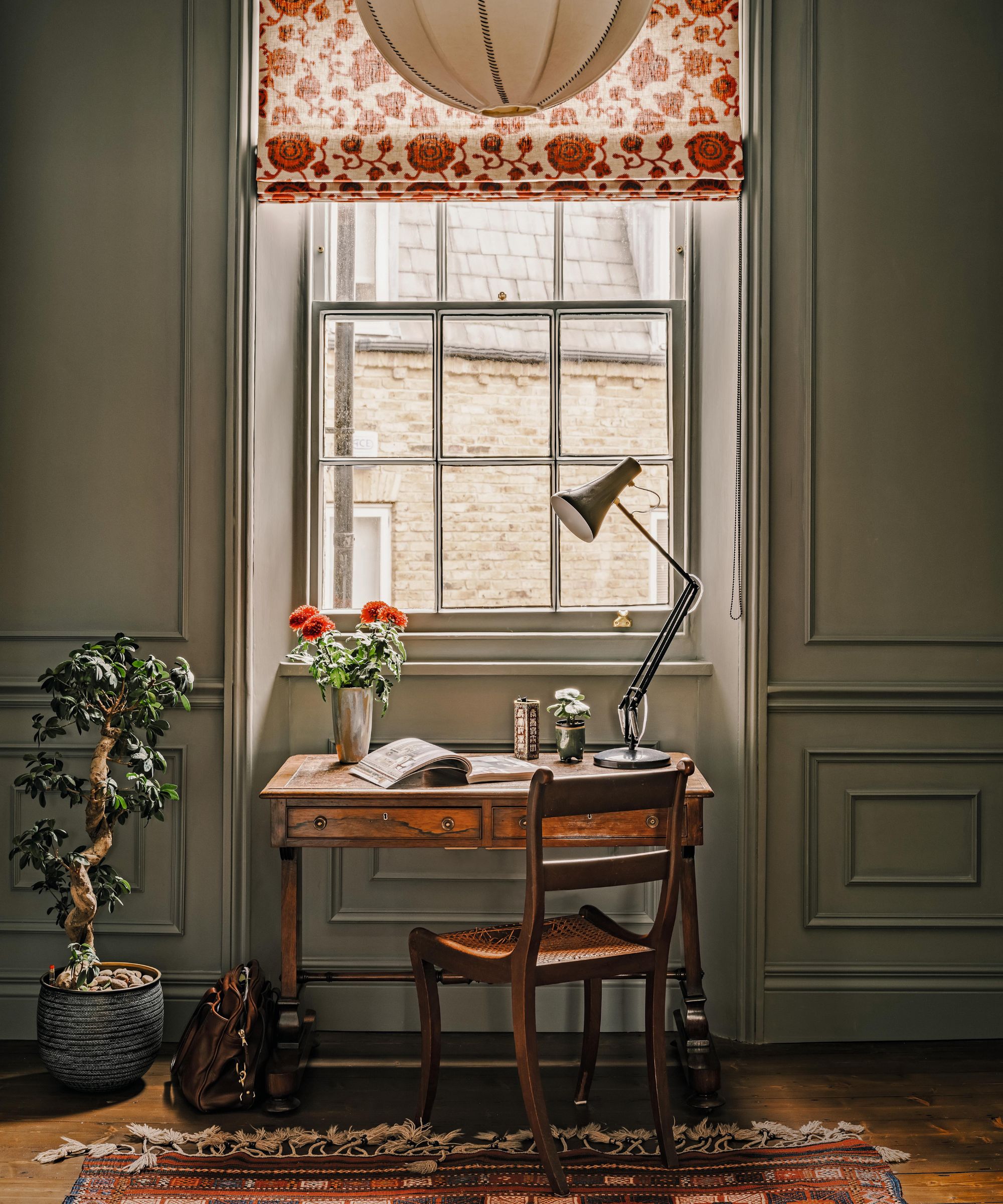 a green gray home office with paneling and a small antique desk