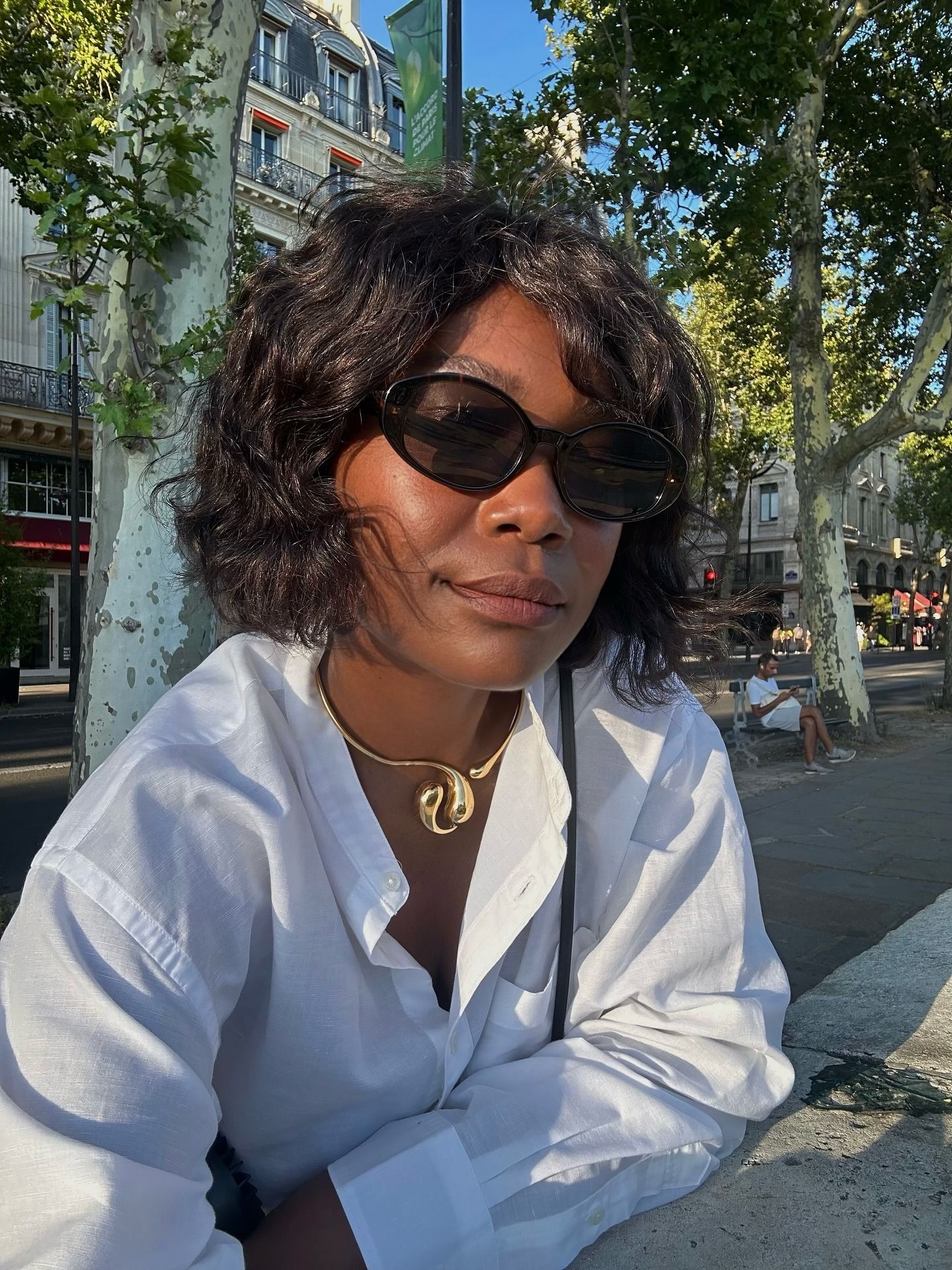 A woman taking a selfie in Paris with a curly, swept bob hairstyle