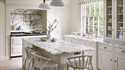A fully white kitchen with white marble countertops and island