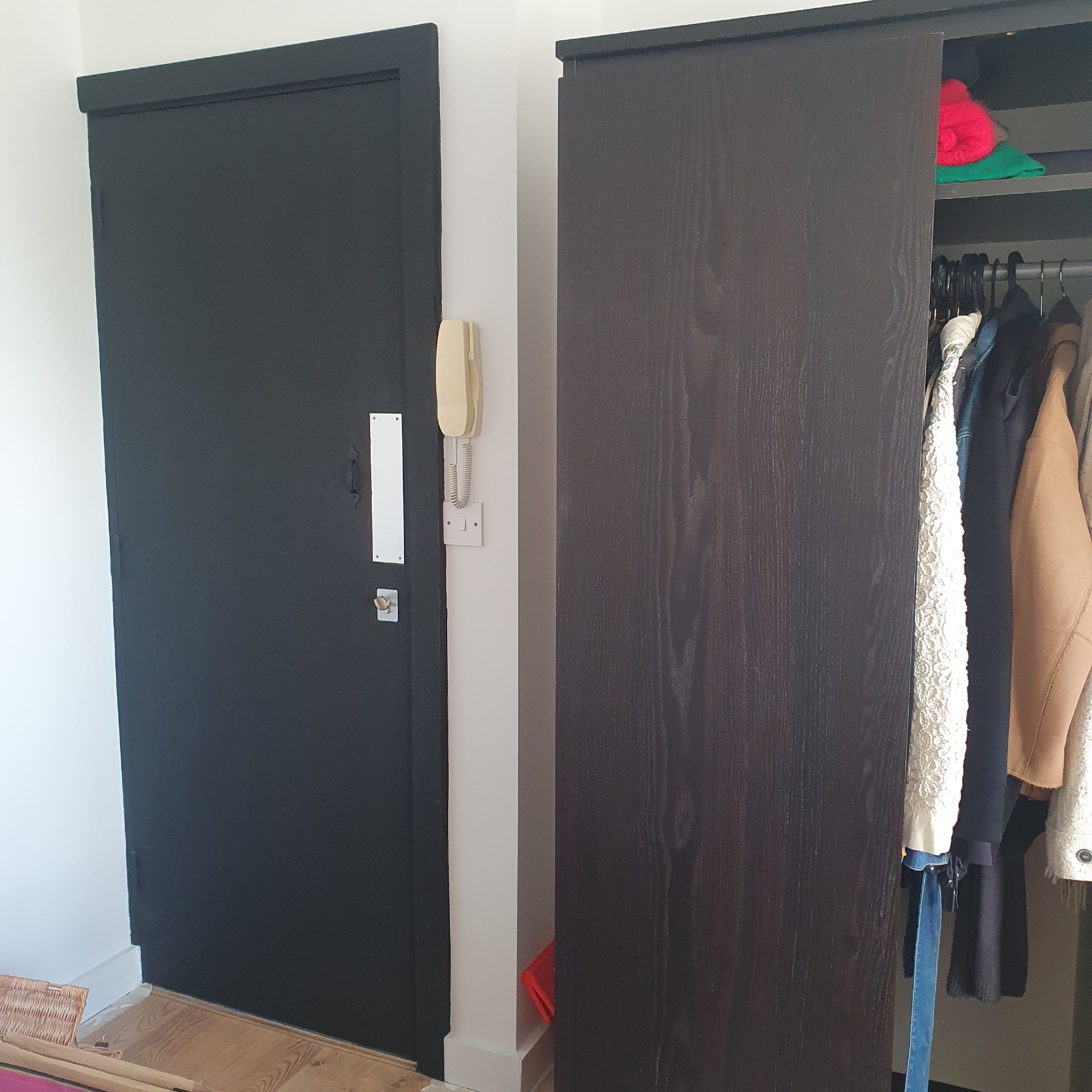 The before: Matt black-painted front door and a black wardrobe next to it 