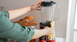 Woman wiping the base unit of a kitchen blender