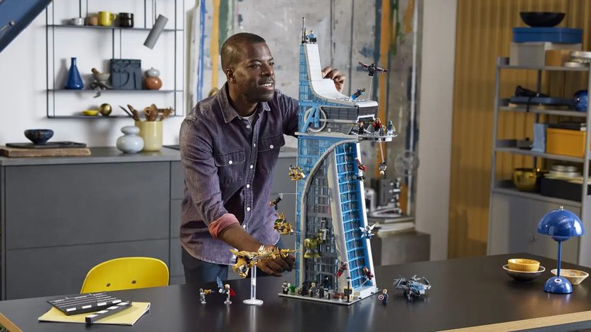 A lifestyle shot of the Lego Marvel Avengers Tower, showing a man placing the finishing touches on the top