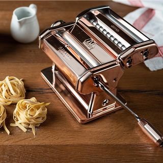 pasta maker with white cup on wooden table