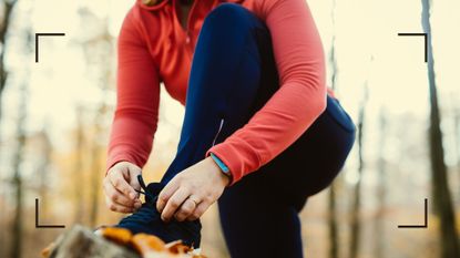 Woman lacing up shoes outdoors in the forest to work out with a cold 