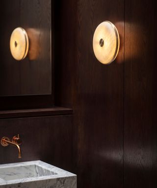 An example of bathroom lighting trends showing a close-up shot of bathroom wall lighting in a dark bathroom