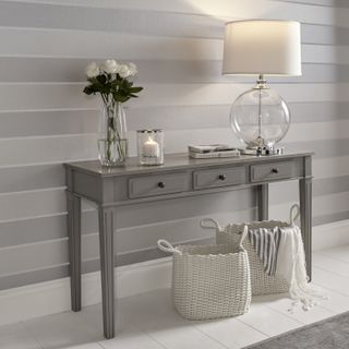 striped grey and silver toned wallpaper with grey side table and glass accessories