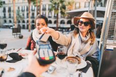 Woman paying in restaurant with cards for travel abroad