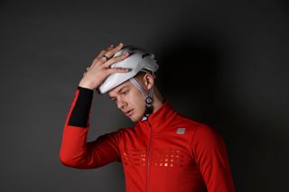 Male cyclist holding his head which is one of the symptoms of someone who has a concussion