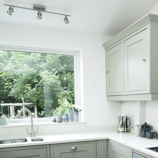 A light kitchen with a large window and spotlights above the sink