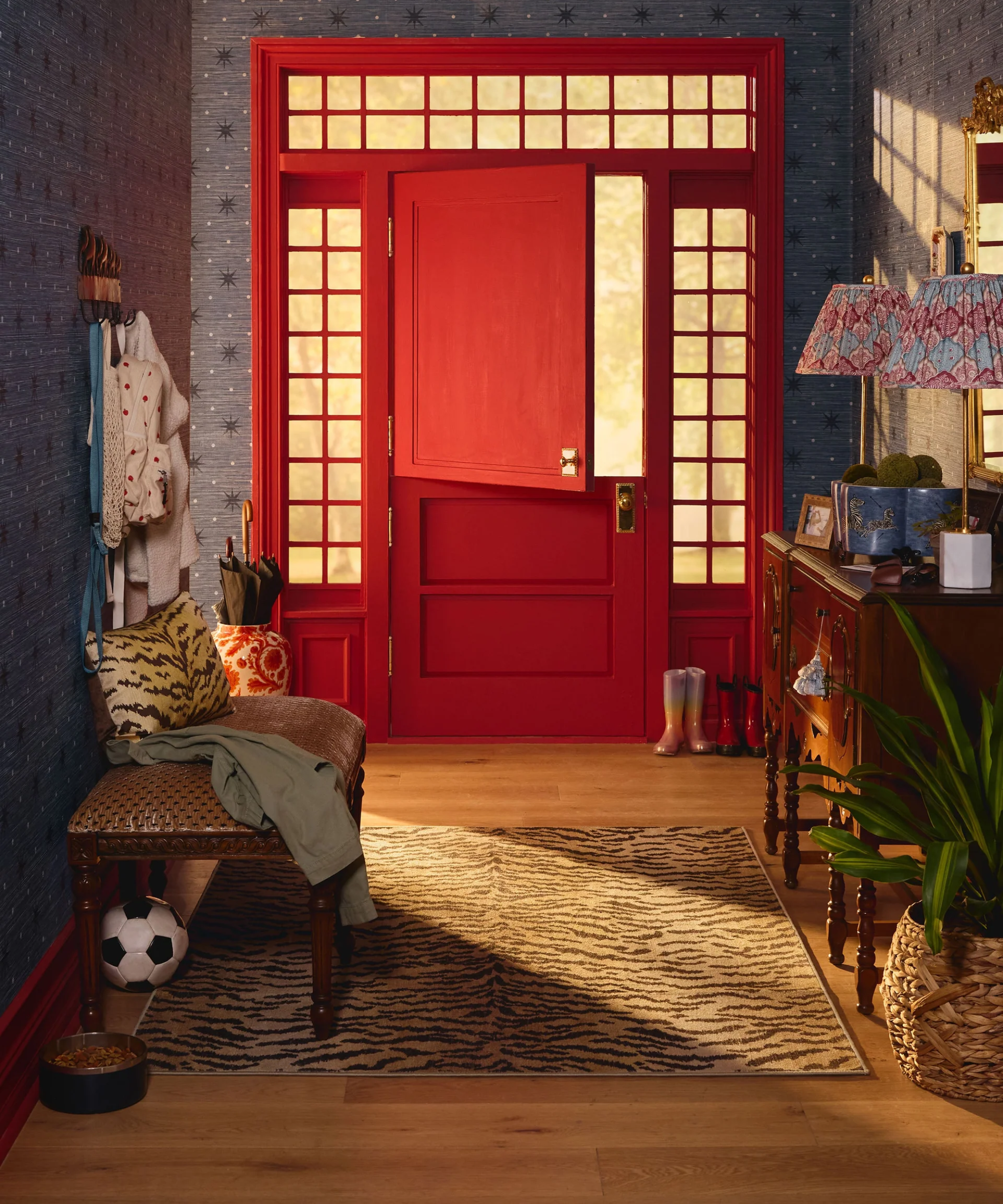 Bold entryway featuring a bright red front door, an antique bench styled with personal objects, and a tiger print rug