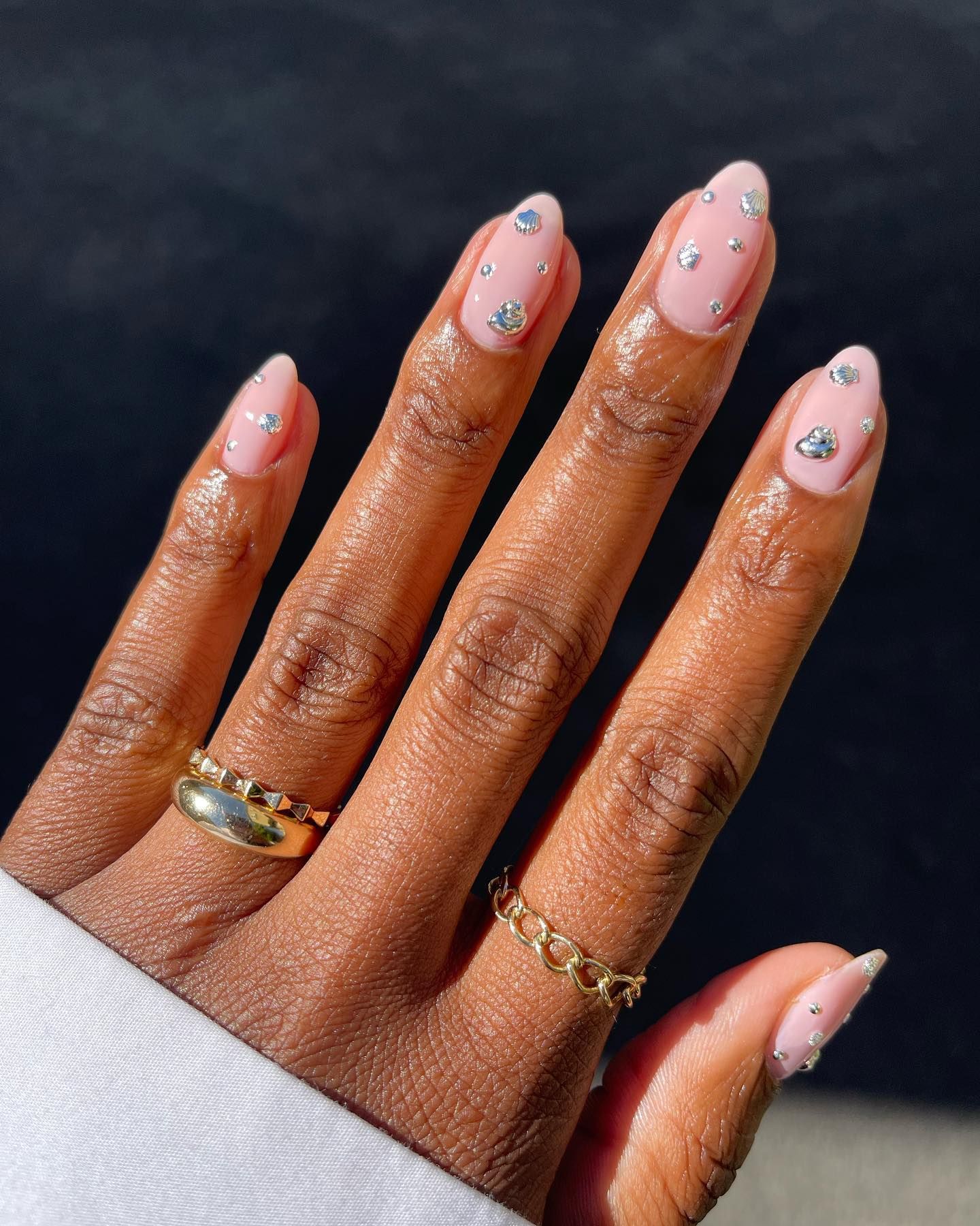 A pale pink manicure with silver gems.