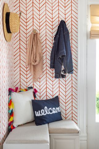 small mudroom with chevron wallpaper and coats/hat hanging bench seat