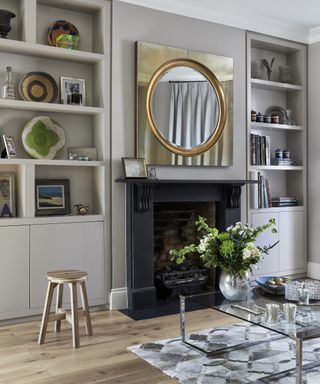 A living room mirror idea with a circular mirror with a square gold frame