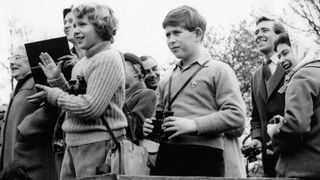 Princess Anne and Prince Charles watch one of the competitors taking part in the cross country event in 1960