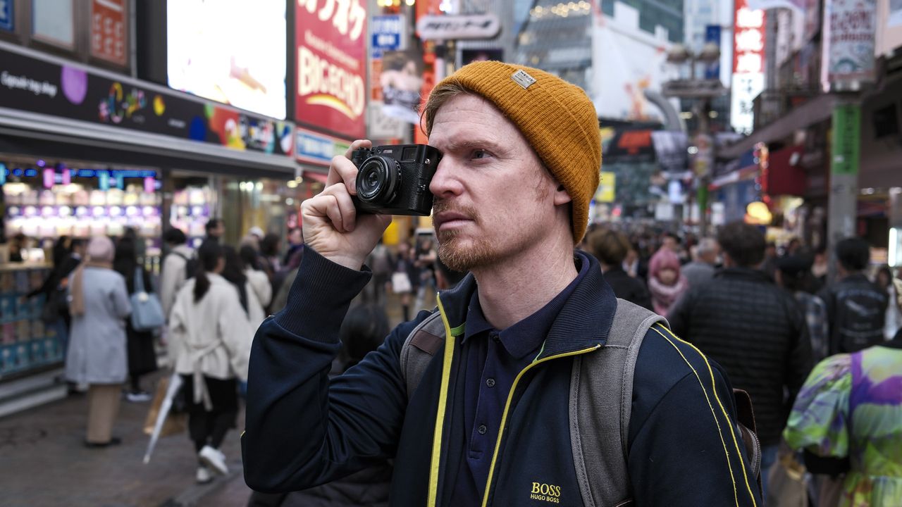 Fujifilm X100VI camera held up to photographer's eye on the streets of Tokyo