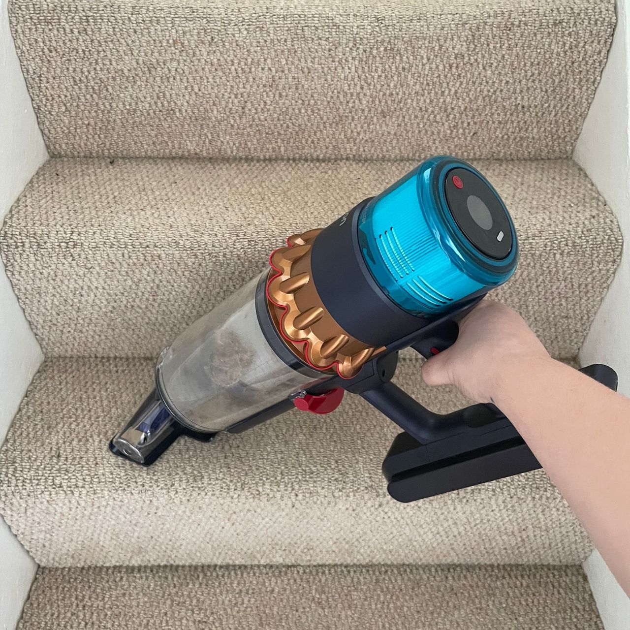 Using the Dyson Gen5detect handheld section on cream carpeted stairs