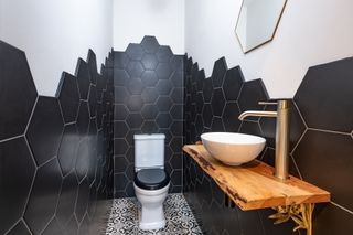 narrow downstairs bathroom with black hexagonal tiles