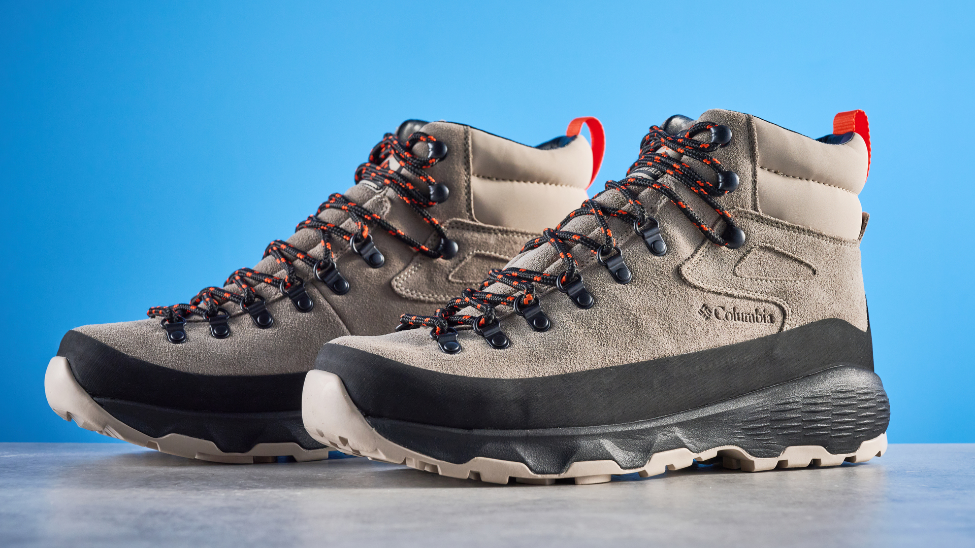 The Columbia Newton Alpine boots on a stone surface with a blue background