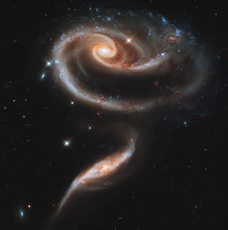 Two interacting galaxies form a rose-like shape, captured by the Hubble telescope.