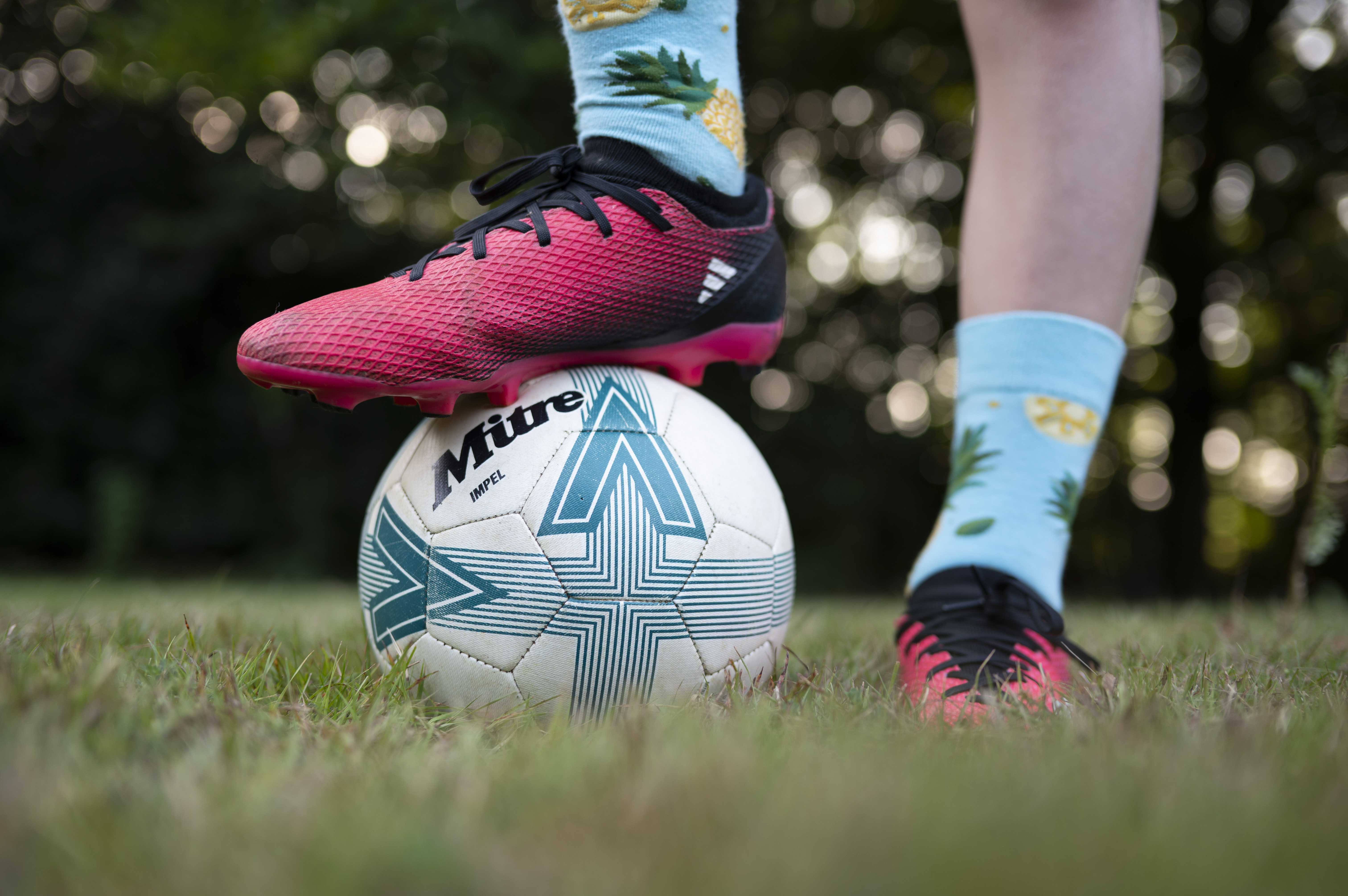 Closeup of a footballer's feet, with one foot standing on top of a ball