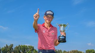 Martin Couvra holds a trophy and holds up his finger