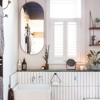 Think white vertical tiles in bathroom with window and oval mirror