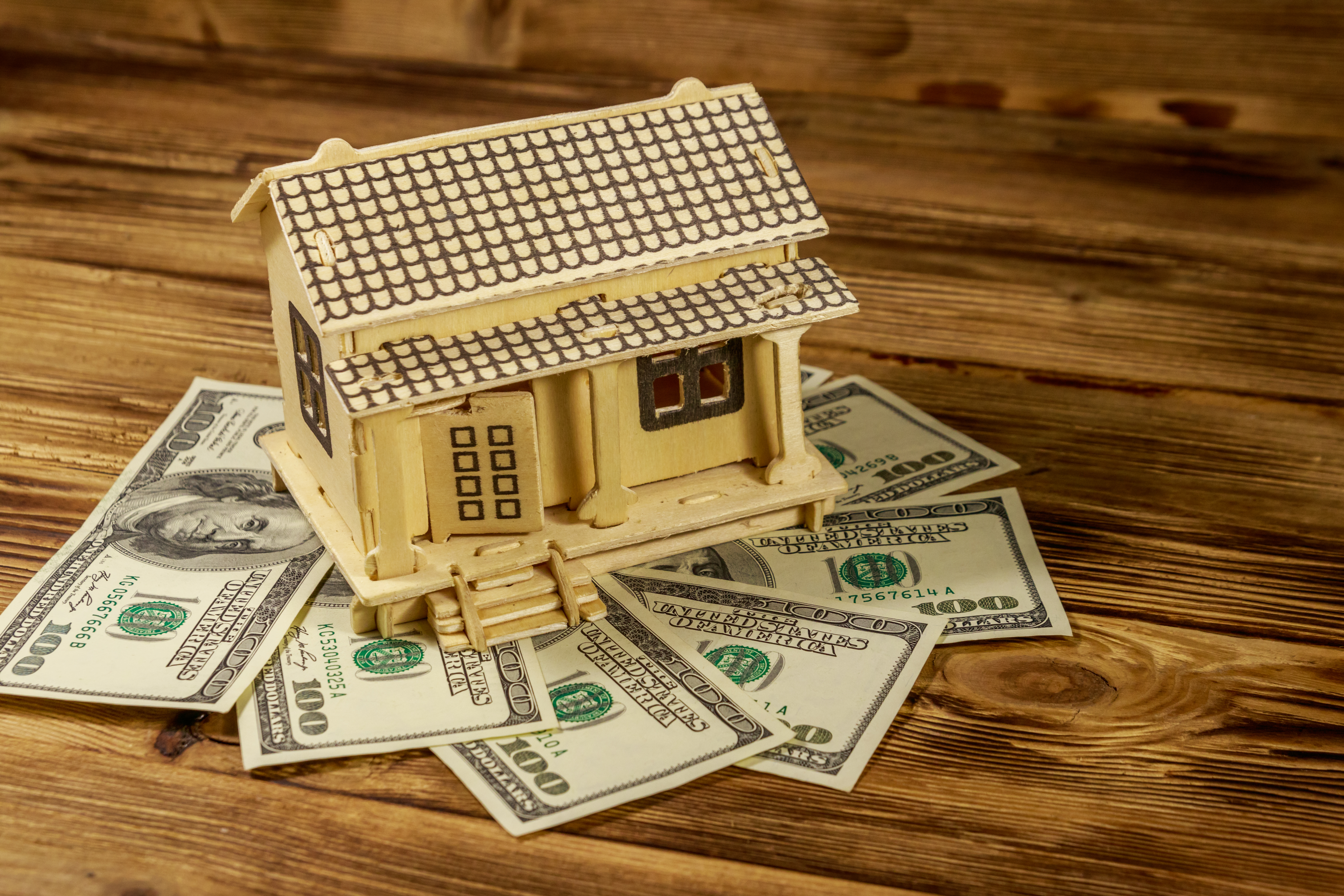 A model house sitting on top of a pile of money.
