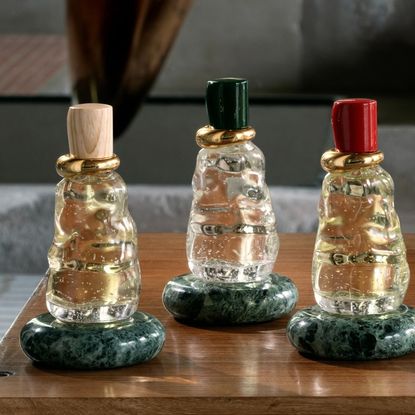 three Bottega Veneta glass fragrance bottles on green marble base