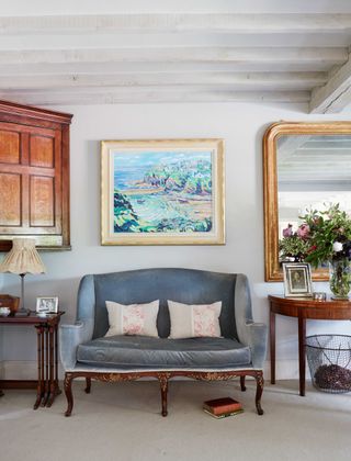 velvet sofa in living room with wooden antique furniture and mirror and artwork