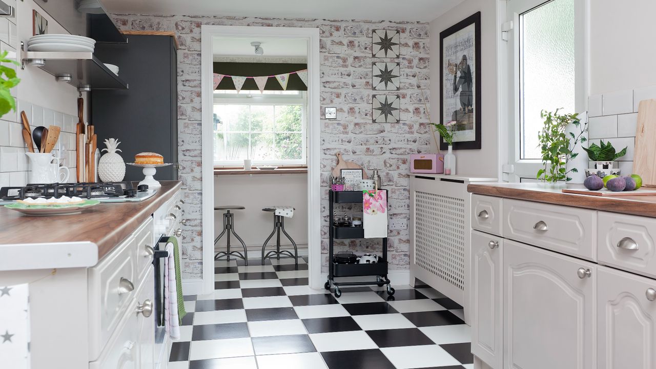 Black trolley displaying kitchen utensils next to doorframe in white kitchen