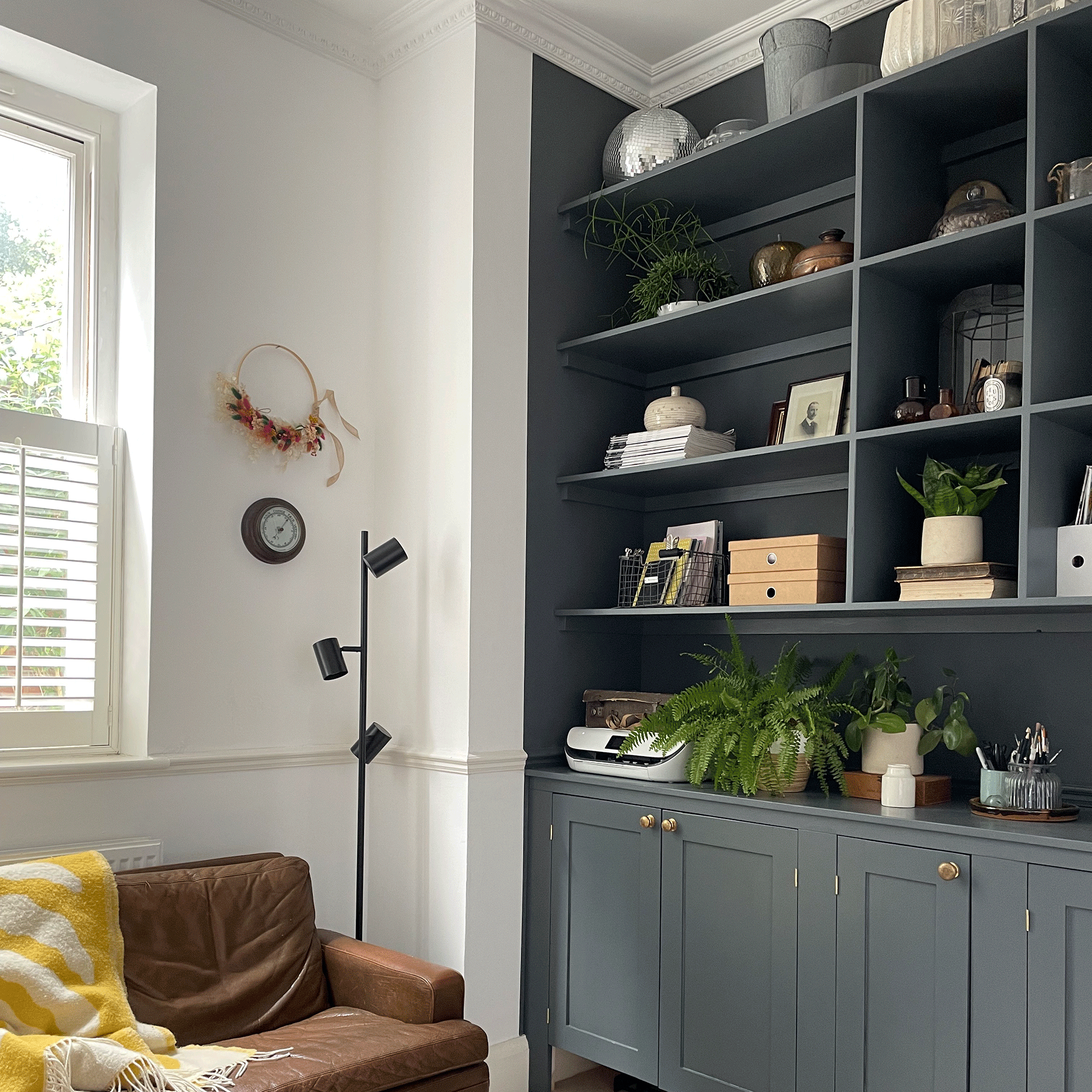 Dark grey shelving with white wall and brown sofa