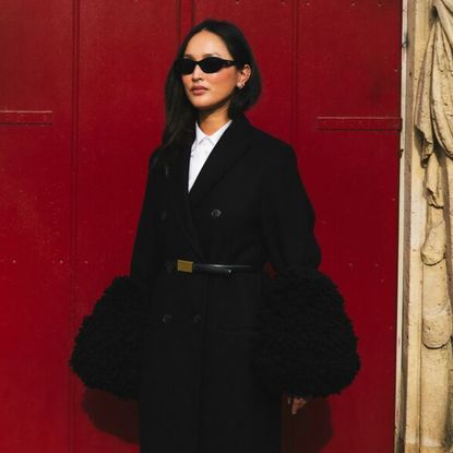 a guest at Paris Fashion Week wearing a fur trimmed coat