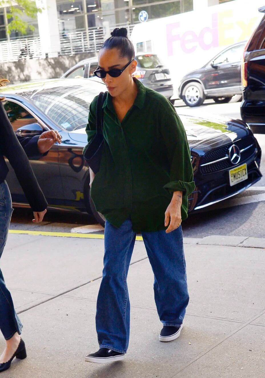 Zoe Kravitz wears a green shirt a blue denim jeans, '90s oval sunglasses, and slip-on vans in an image taken of her in September last year.