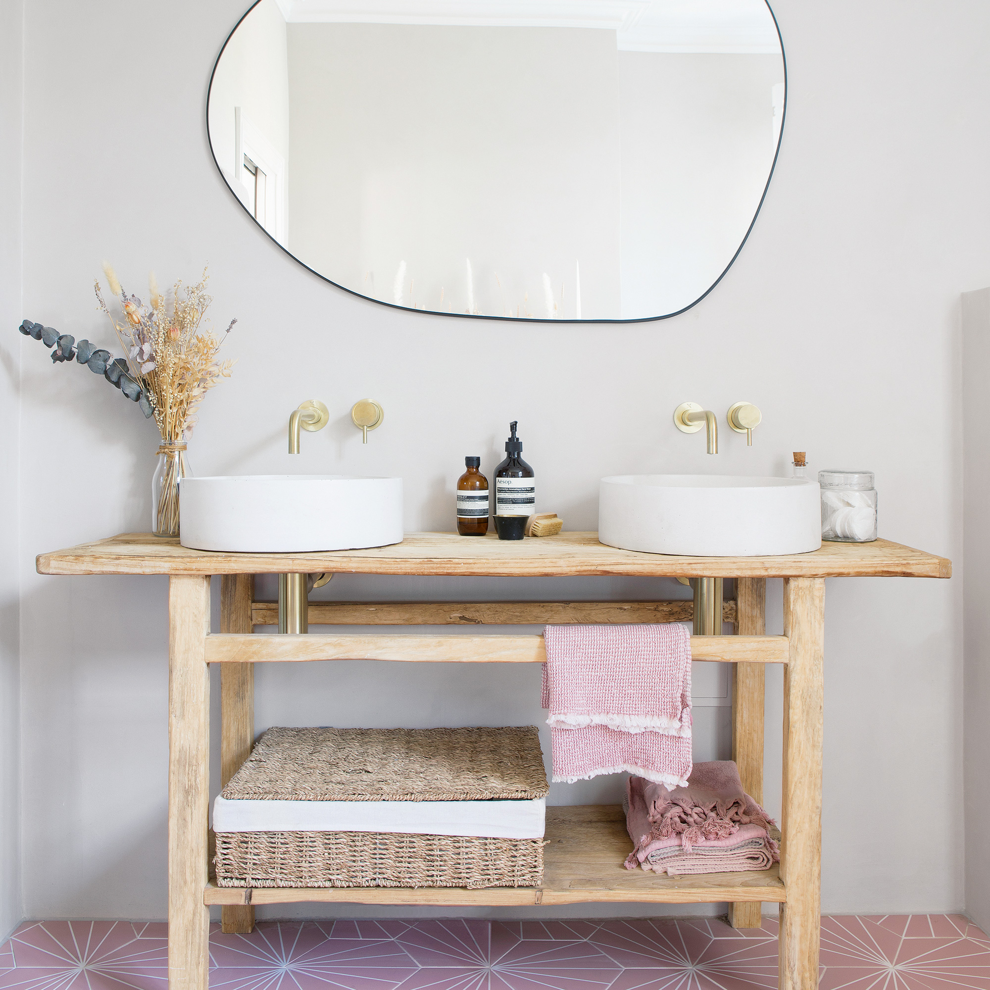 twin round bathroom basins on a pale wood table base and large mirror