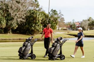 Two golfers using the Stewart Vertx Remote trolley on a golf course