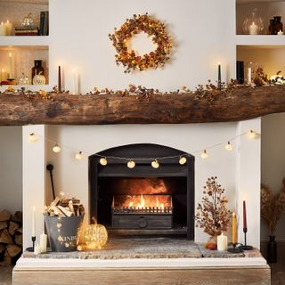 living room fireplace with autumnal fall decor, candles and pumpkins