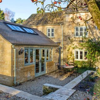 Exterior of stone cottage, looking at the house from a patio