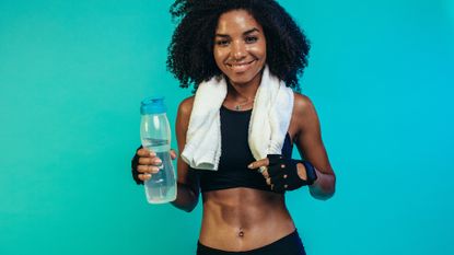 A woman cooling down and drinking water after doing a flat stomach workout