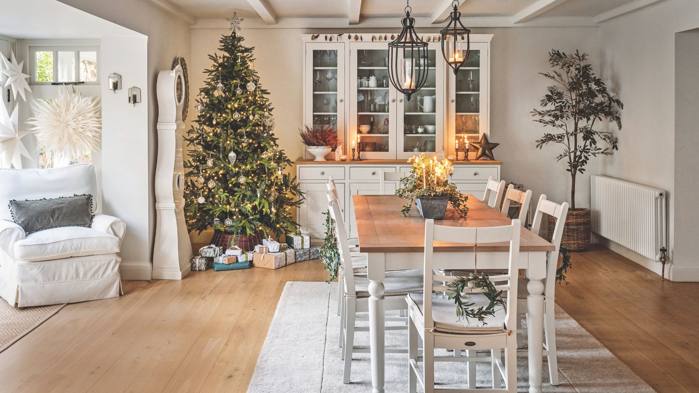 Dining room decorated for Christmas with a tree behind the wooden dining room table