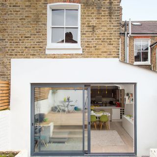 Rear of brick terraced house with white open plan kitchen-living room extension