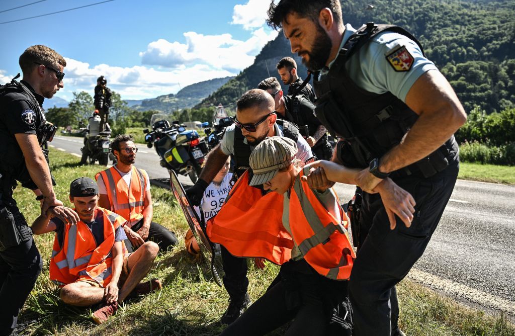 French gendarmes remove environmental protestors from the race route as their protest action temporarily immobilized the pack of riders during the 10th stage of the 109th edition of the Tour de France cycling race 1481 km between Morzine and Megeve in the French Alps on July 12 2022 Photo by Marco BERTORELLO AFP Photo by MARCO BERTORELLOAFP via Getty Images