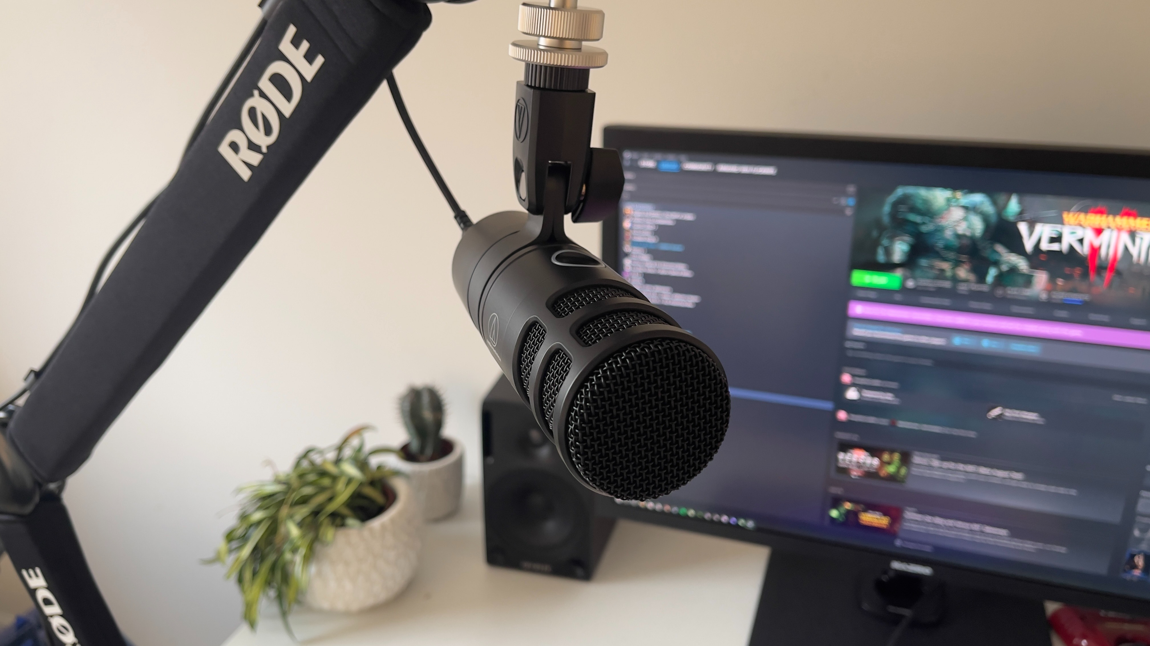 The Audio-Technica AT2040USB microphone on a mic stand in front of a monitor