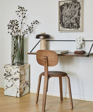 A small desk attached to the wall with a wooden chair in front