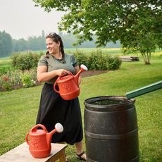 woman using rainbarrel to fill watering cans for garden 